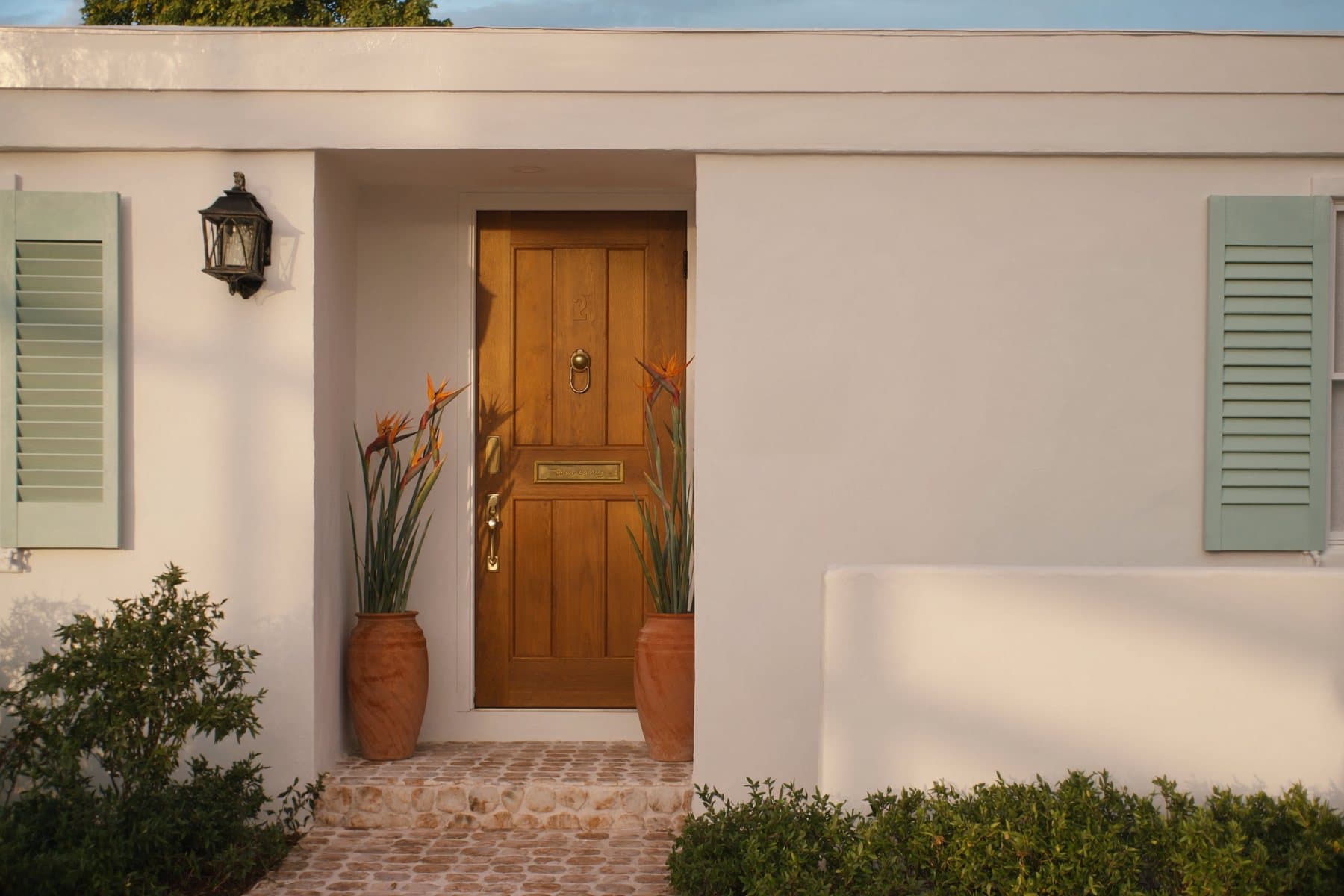 Teak front door of a stucco rental home in Southwest Florida at golden hour